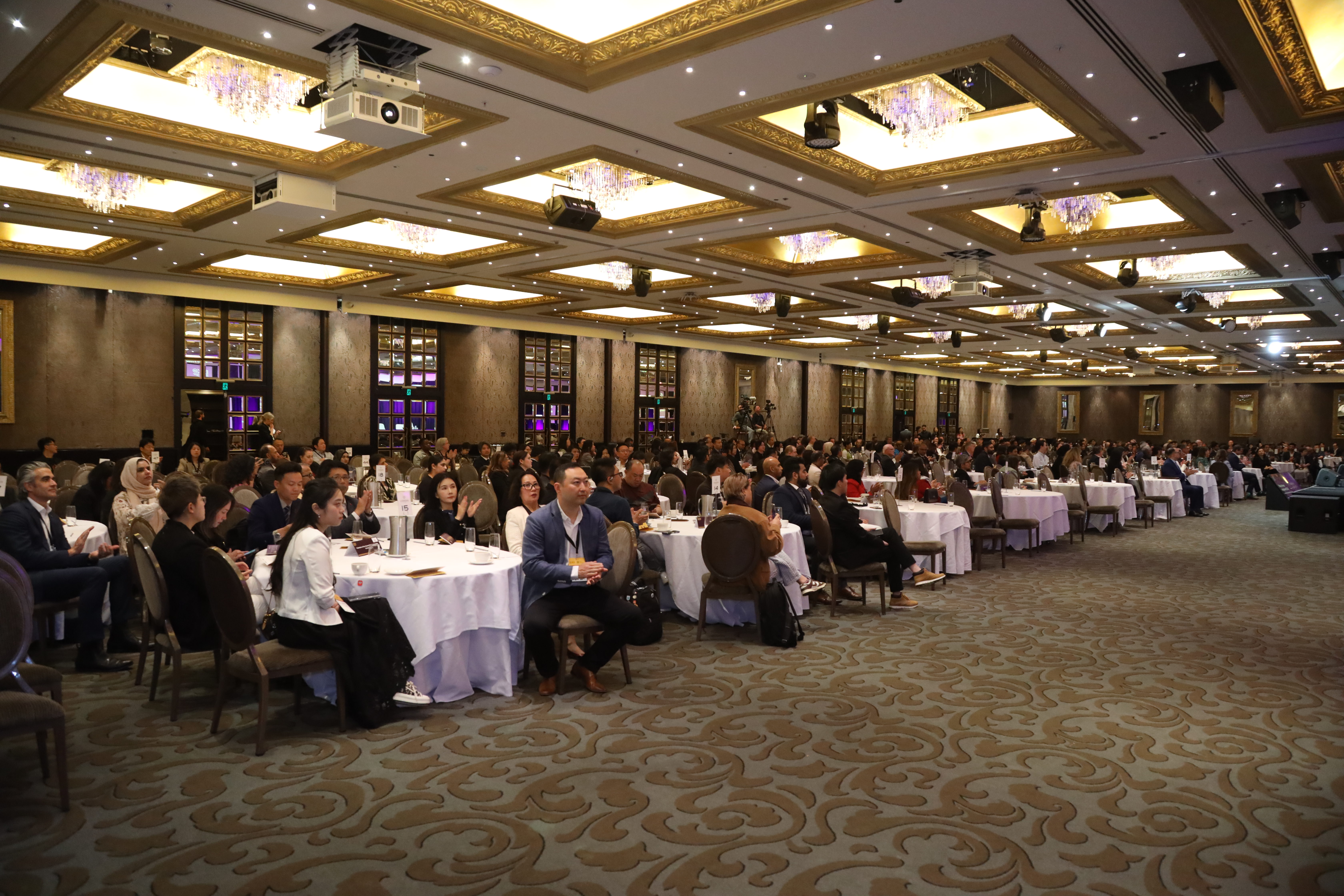 People sit at tables in a large conference room.