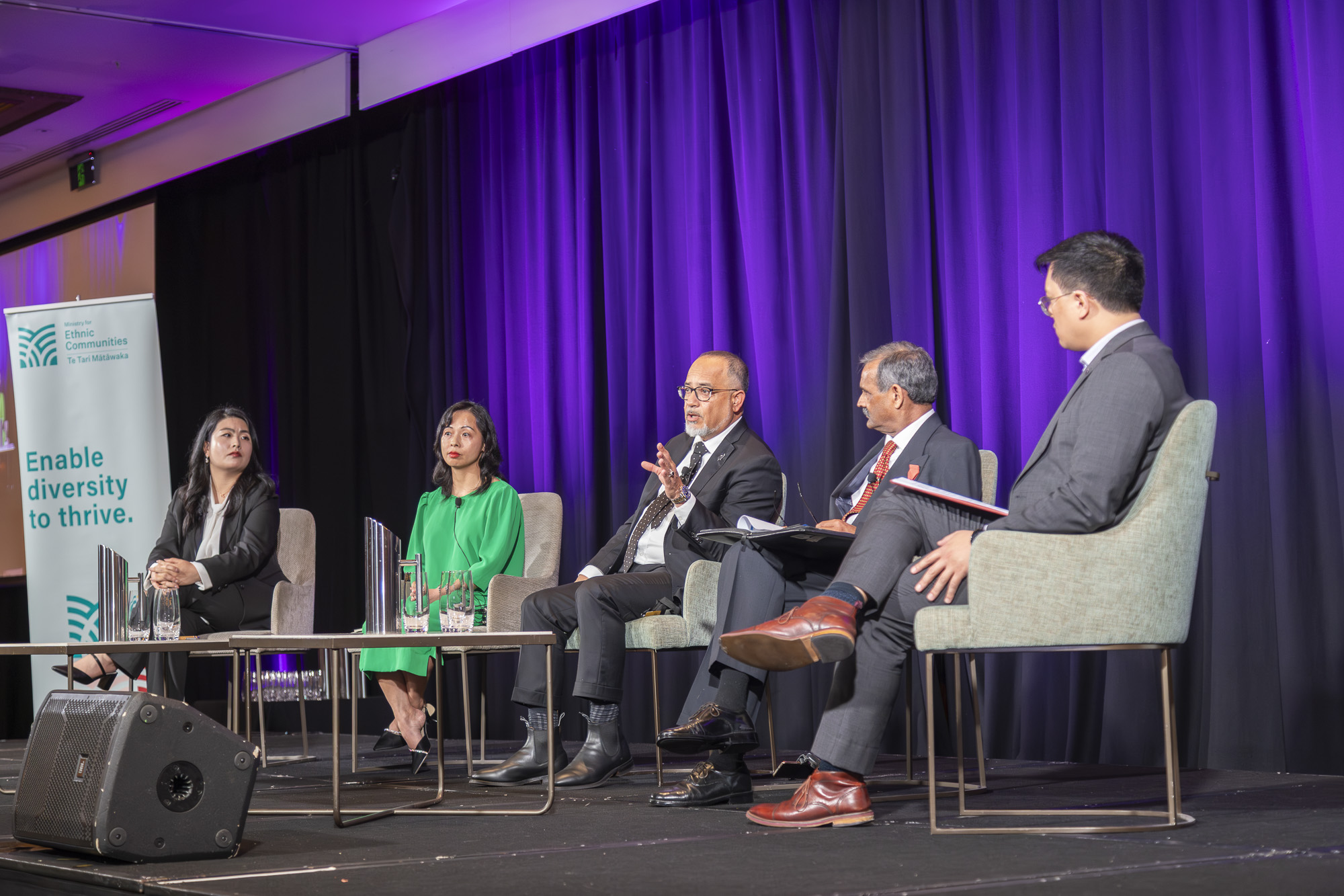 Five people sit on stage talking.