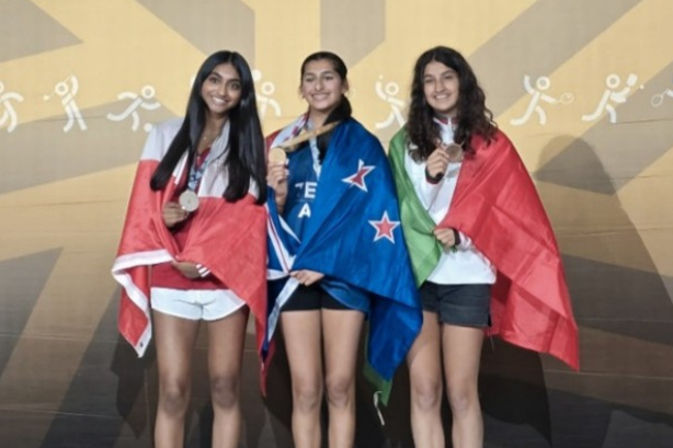Three medalists stand on a 2025 podium, each holding a medal and wrapped in their national flags.