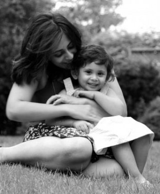 Woman with a child in her lap - cuddling on the grass.