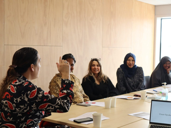 Women's Leadership training course - faciliator describing to women seated at a table.