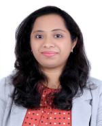 Person with long, wavy black hair wearing a light gray blazer and a red polka dot blouse, with their face blurred out. 