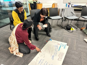 Photograph of hui participants engaging in conversation in a small conference room.